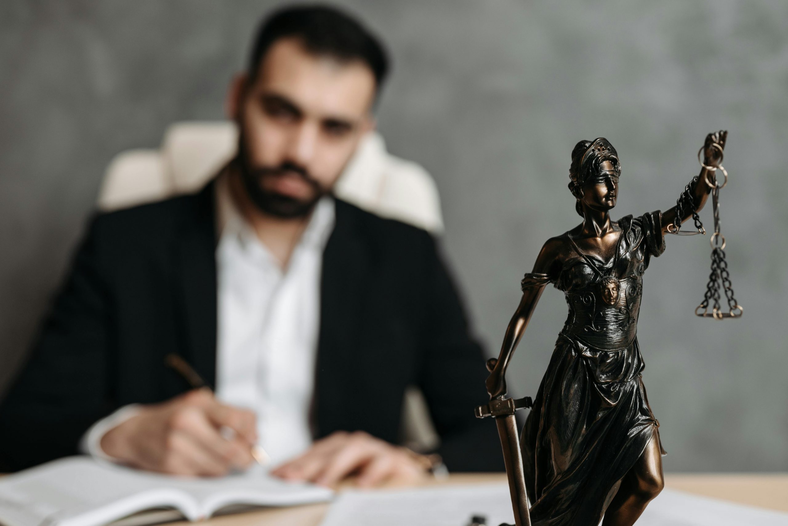male lawyer sitting at a desk with a decorative Lady Justice figurine