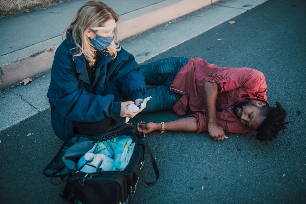man lying on the ground receiving medical attention after a fall