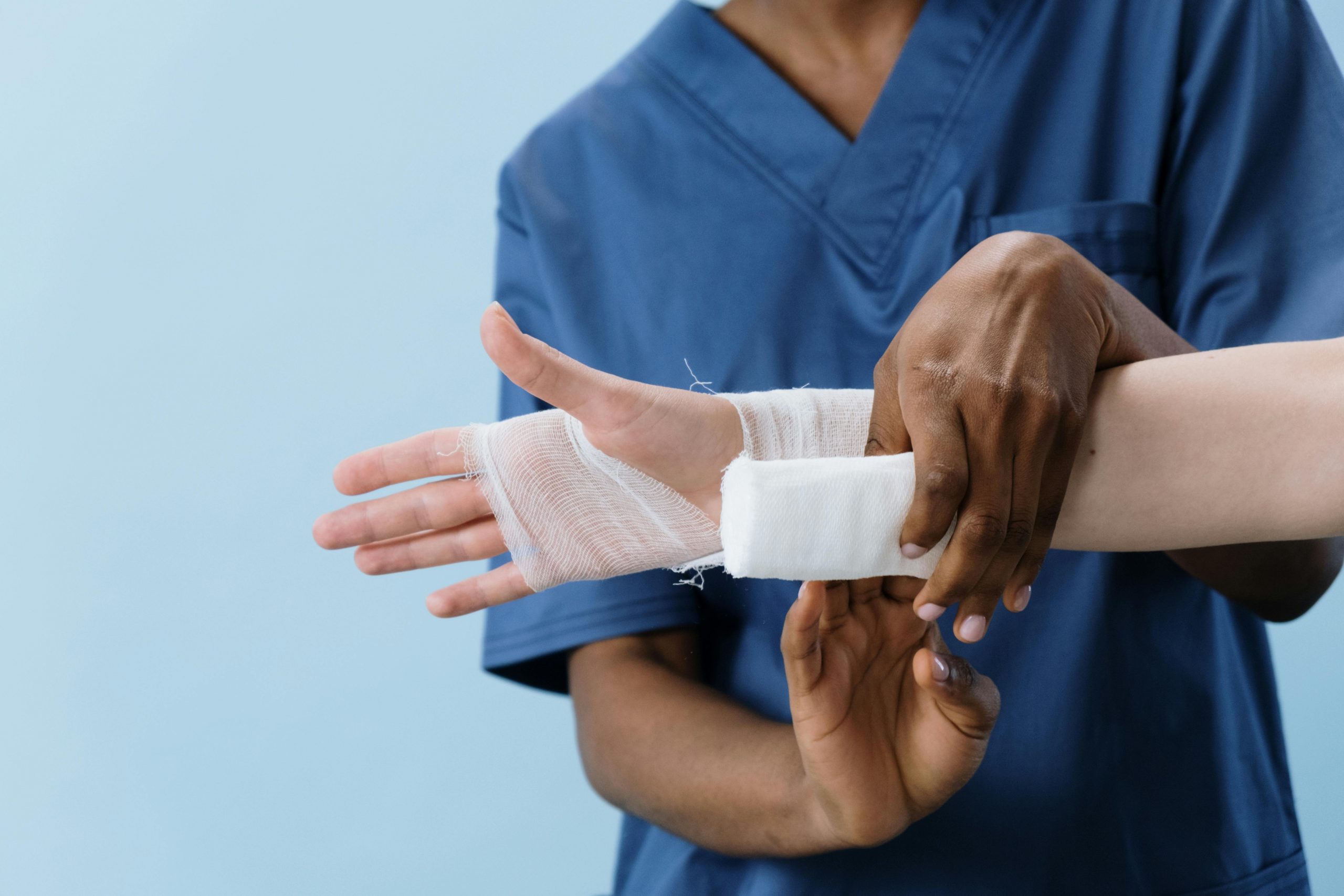 healthcare professional wrapping a bandage around a patient's hand