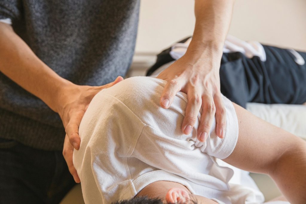 physical therapist treating a patient lying on a bed